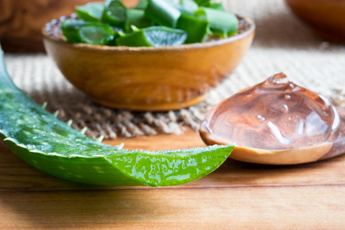 aloe vera plant and gel on wooden spoon and in bowl on tabletop