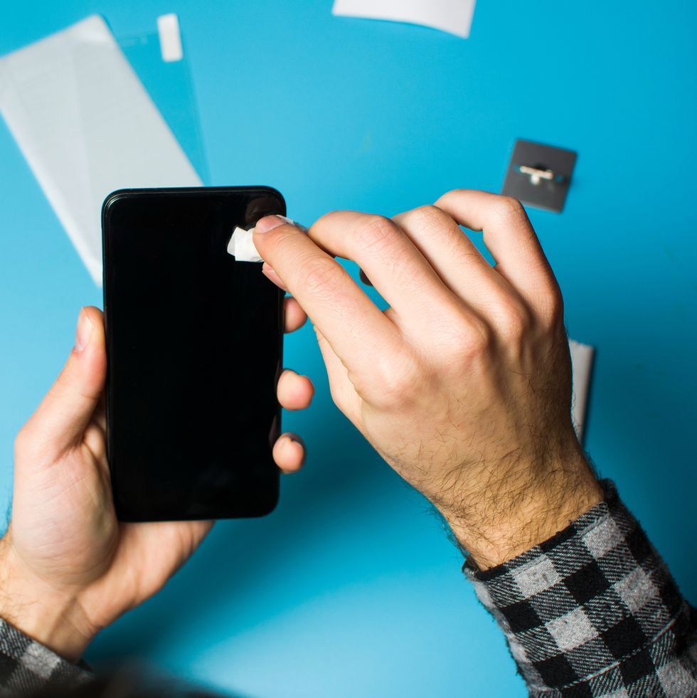 man cleaning phone screen to apply protective glass royalty free image 1583354059 1