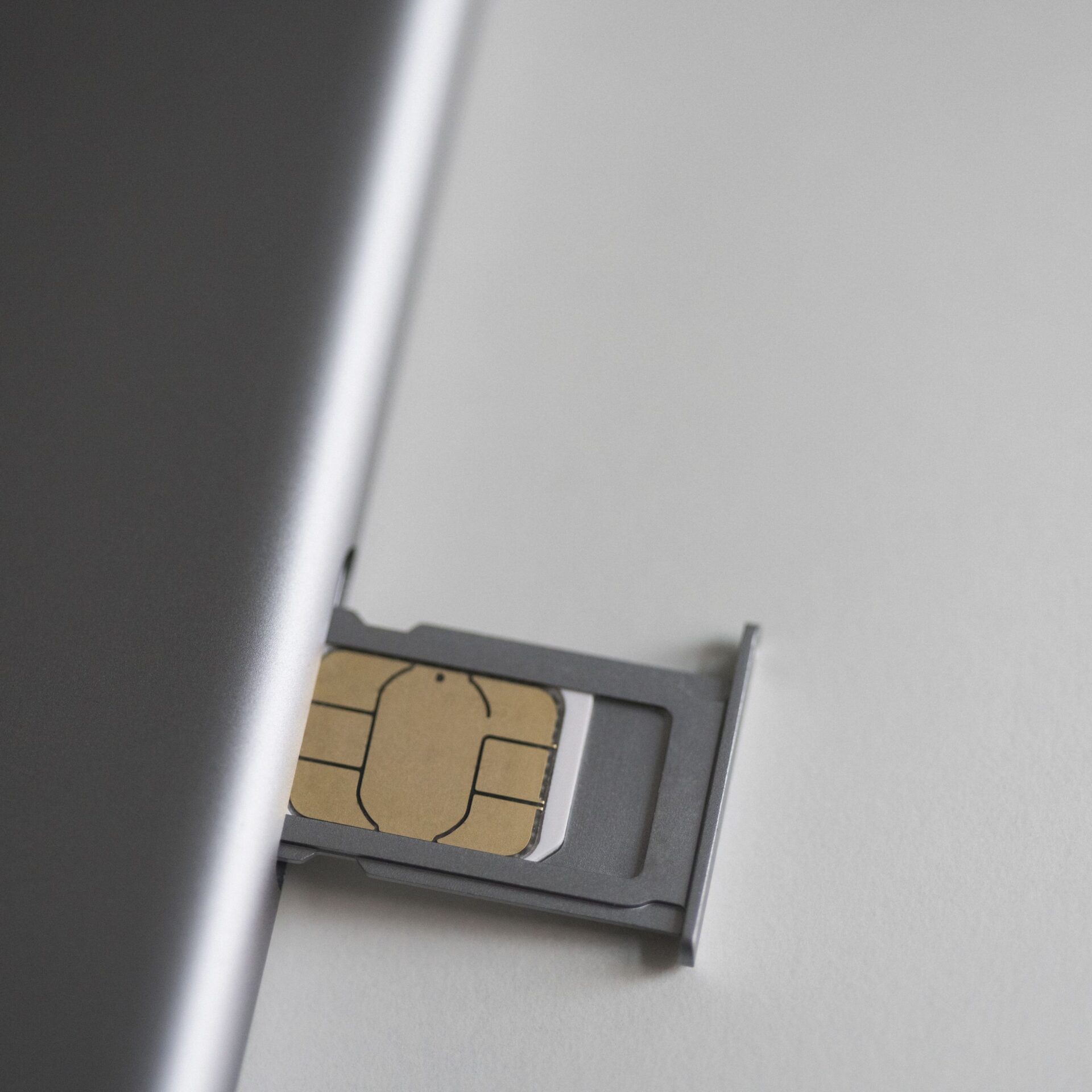 close up of sim card and mobile phone on white table 743692241 5c4cc359c9e77c0001f321e7 scaled